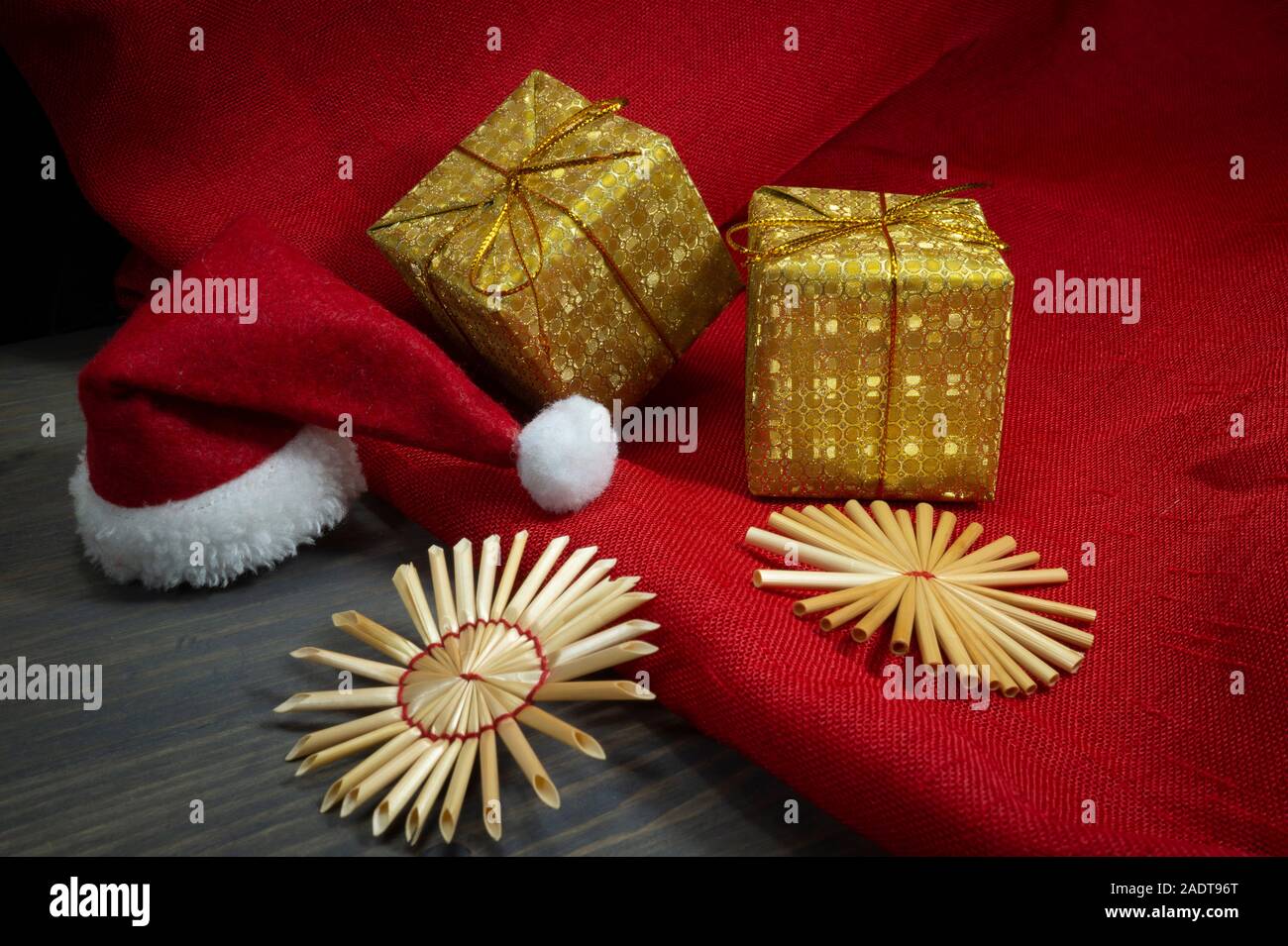 Noël encore la vie rustique avec des ornements de paille d'or, cadeau, une ambiance festive rouge Santa hat, tissu rouge correspondant sur un fond de bois, eco fr Banque D'Images