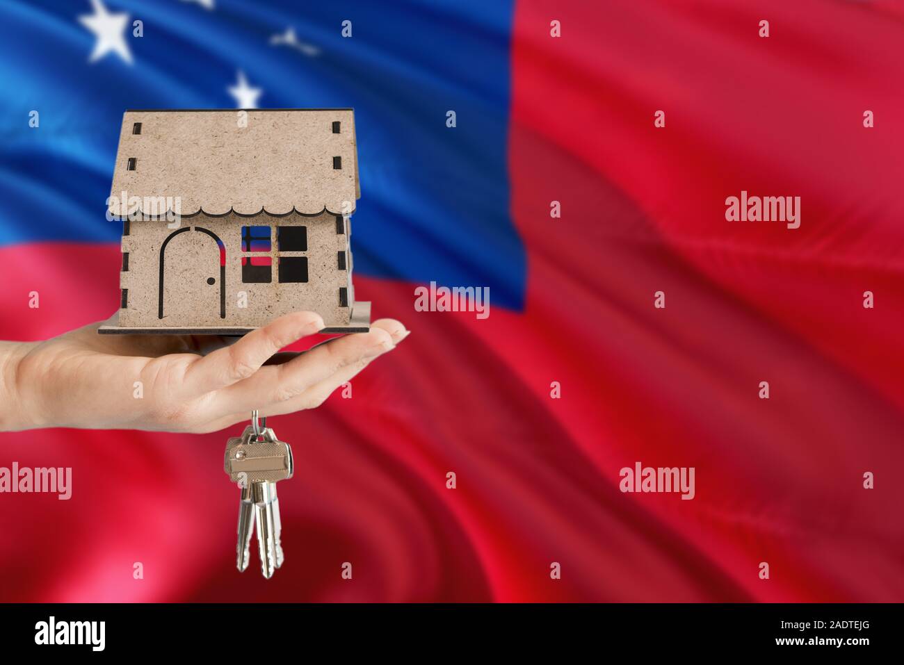 Woman hand holding maison en bois et les touches avec la main. Samoa drapeau avec concept de louer, achat, assurance, immobilier, construction maison écologique. Banque D'Images