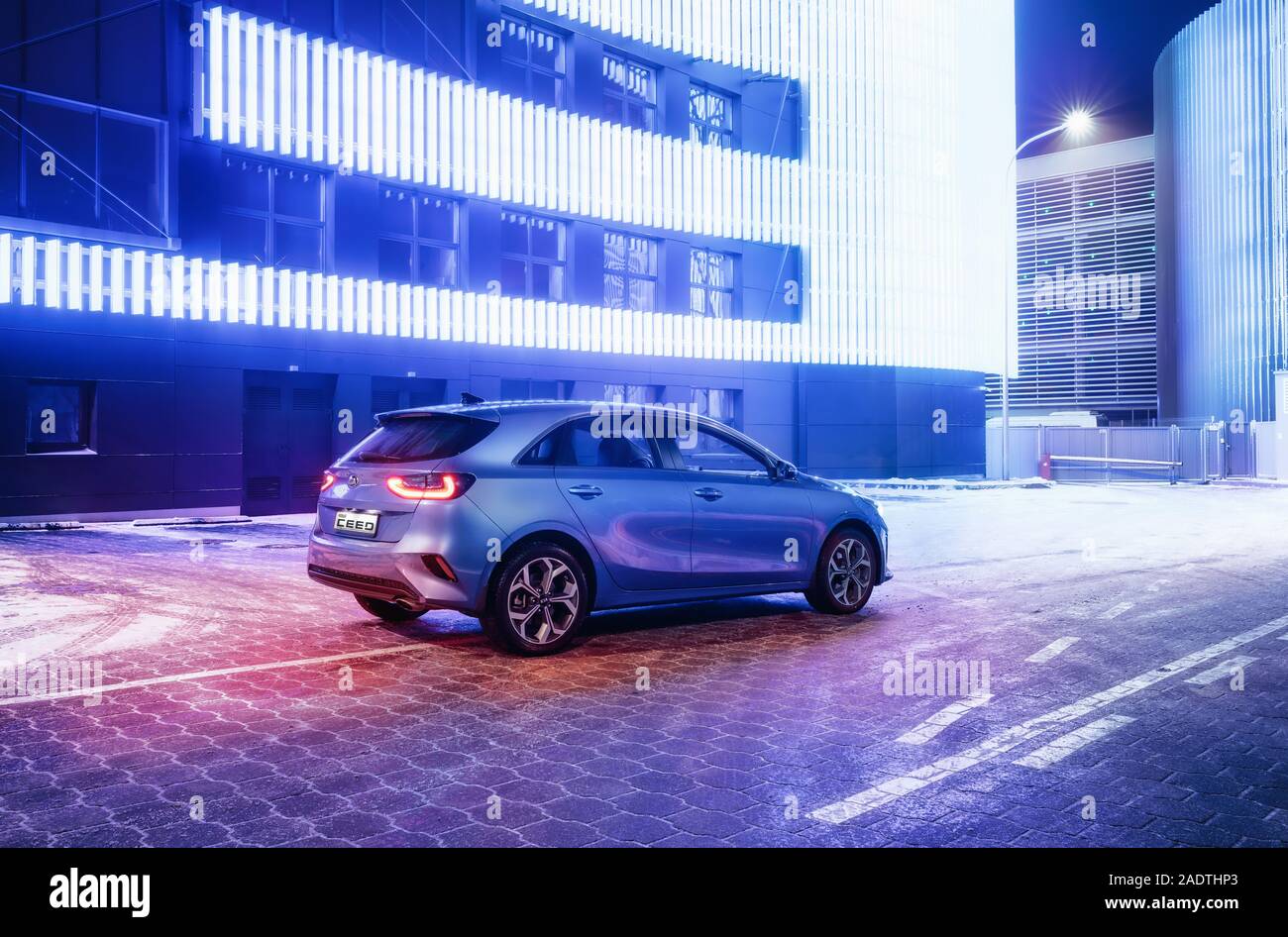 Minsk, Belarus - 26 novembre 2019 : Kia Ceed 2018 voiture sur route enneigée dans nuit ville contre mur avec des lumières de couleur néon Banque D'Images