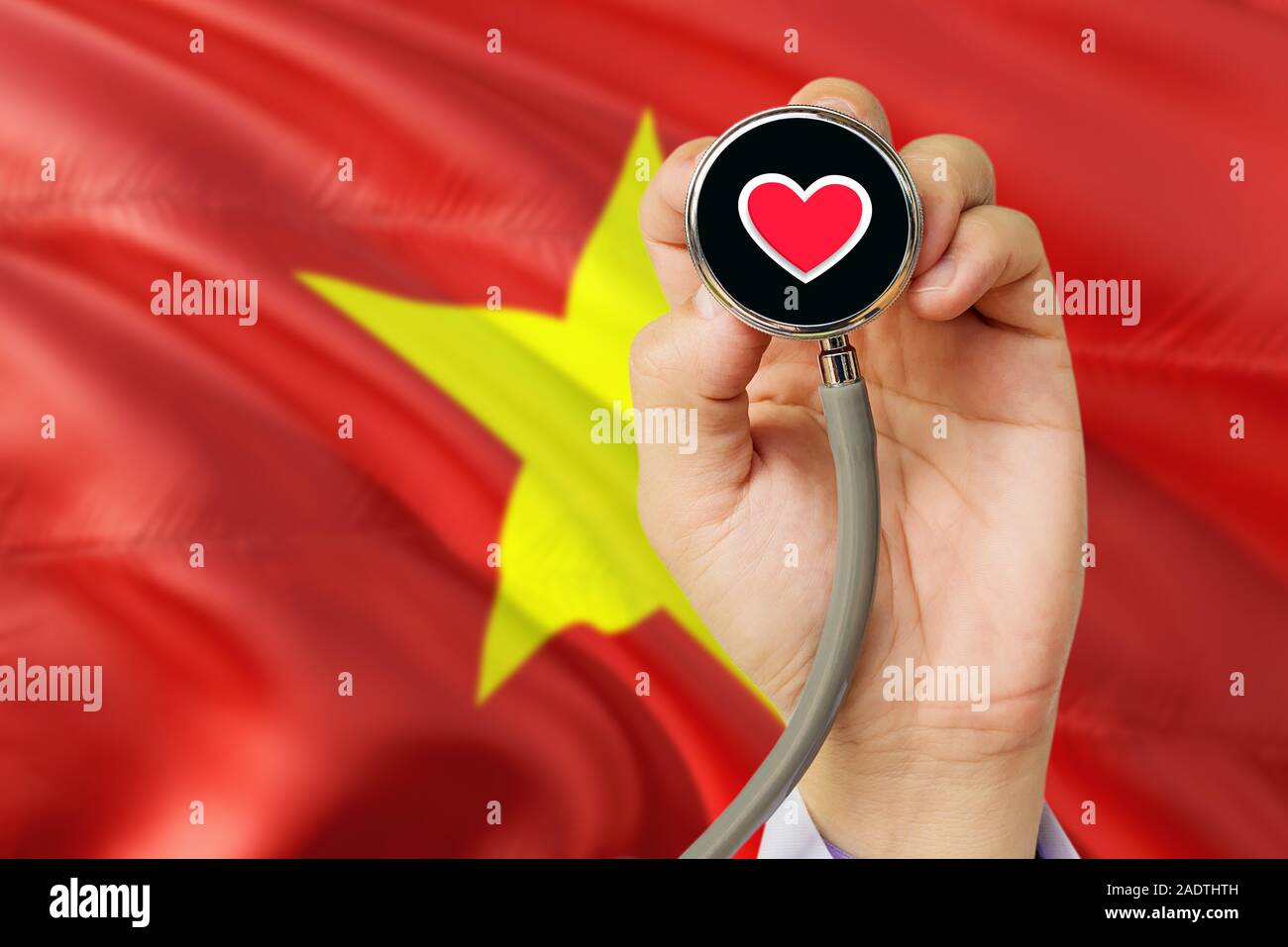 Doctor holding stethoscope avec amour rouge coeur. Drapeau National Vietnam arrière-plan. Système de soins médicaux, concept thème. Banque D'Images