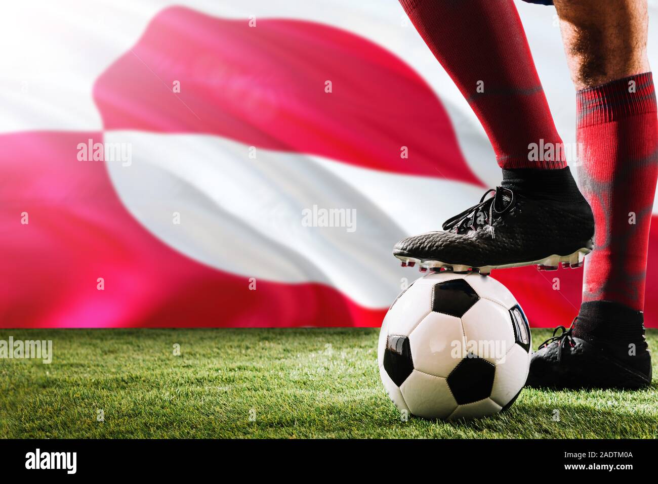 Close up jambes de joueur d'équipe de football du Groenland en rouge chaussettes, chaussures le ballon de soccer au point de penalty ou coup franc jouant sur l'herbe. Banque D'Images