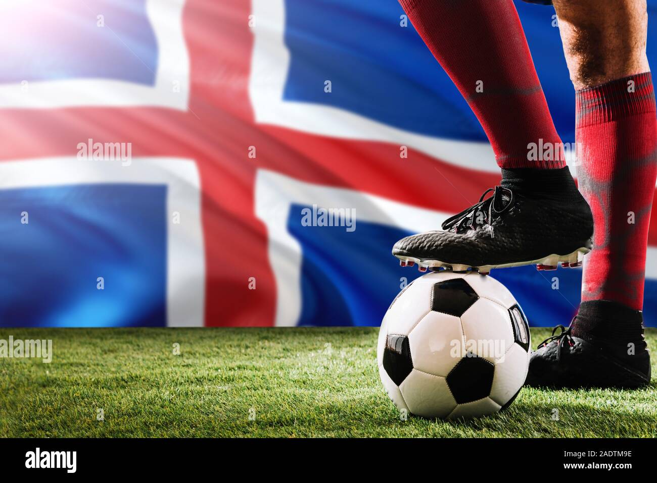 Close up jambes d'Islande de football player en rouge chaussettes, chaussures le ballon de soccer au point de penalty ou coup franc jouant sur l'herbe. Banque D'Images