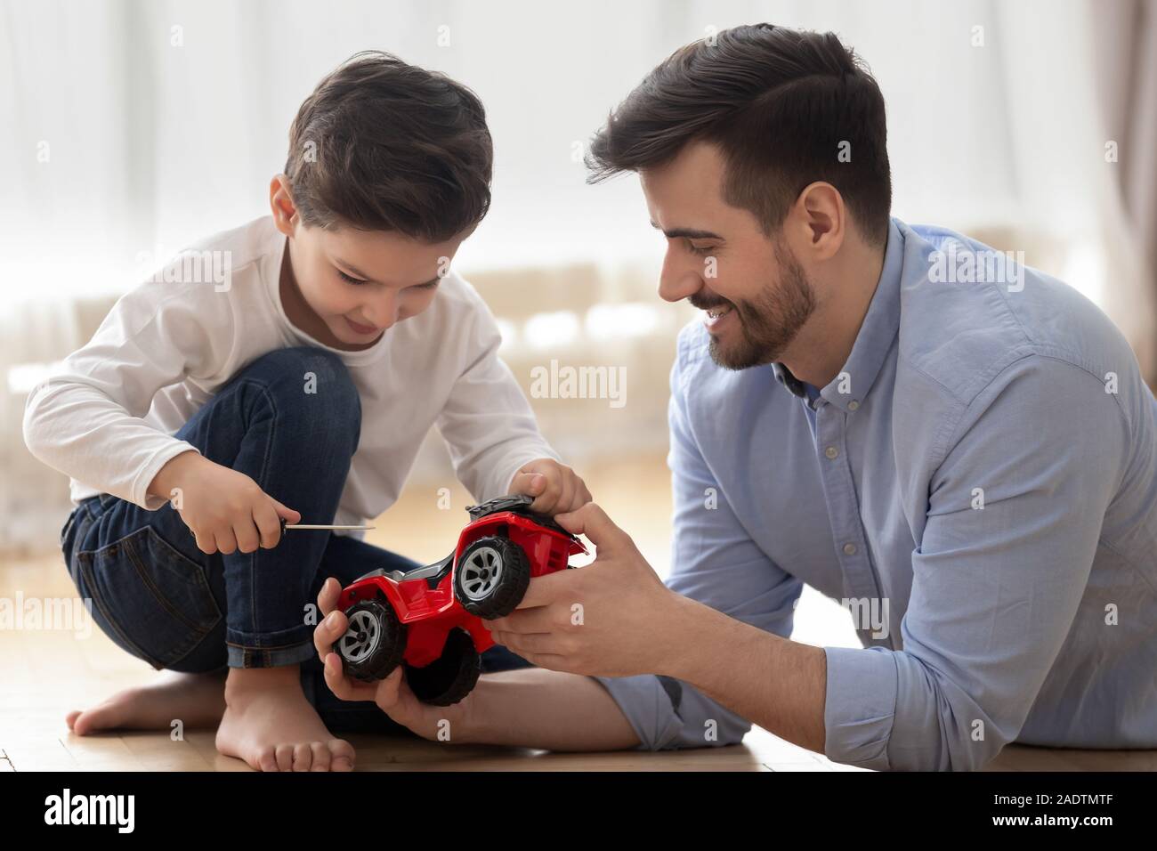Père aide à petit fils réparer toy camion rouge Banque D'Images