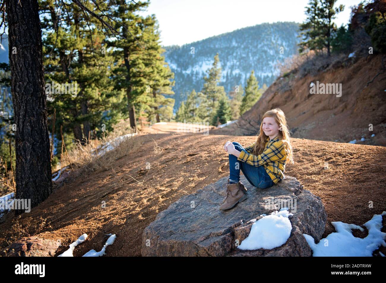 Rousse jeune fille assise sur un rocher au soleil sur Sentier de montagne Banque D'Images