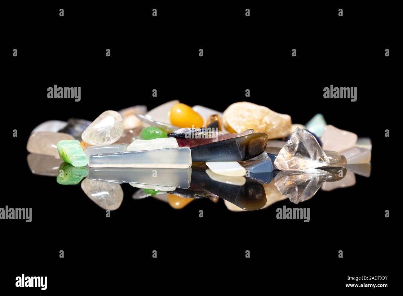 Variété de cristaux colorés, pierres rugueuses et minéraux pierres de guérison, fond noir avec des réflexions Banque D'Images