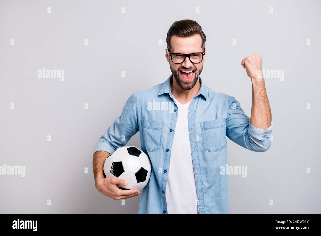 Photo de beau mec beau cuir noir blanc holding soccer ball crier fort soutien d'équipe du football match specs denim casual outfit Banque D'Images