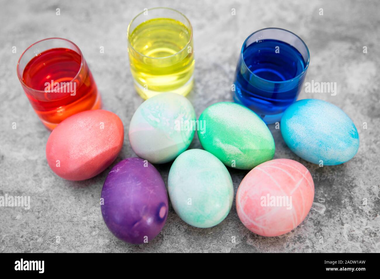 Les oeufs de Pâques colorés et des verres avec des œufs des teintures sur fond gris, vue de dessus Banque D'Images