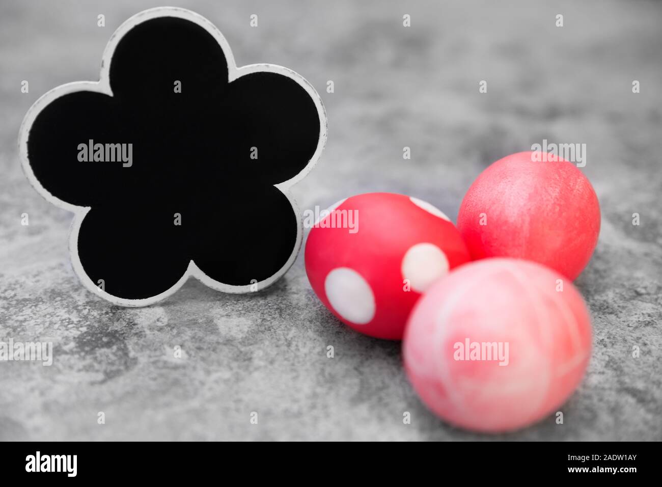 Les oeufs de pâques rose et rouge sur fond gris, en forme de fleur noir ardoise avec copyspace Banque D'Images