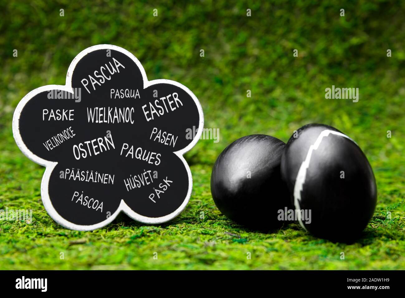 Les oeufs de pâques Noir sur vert prairie, ardoise avec mot easter dans différentes langues Banque D'Images