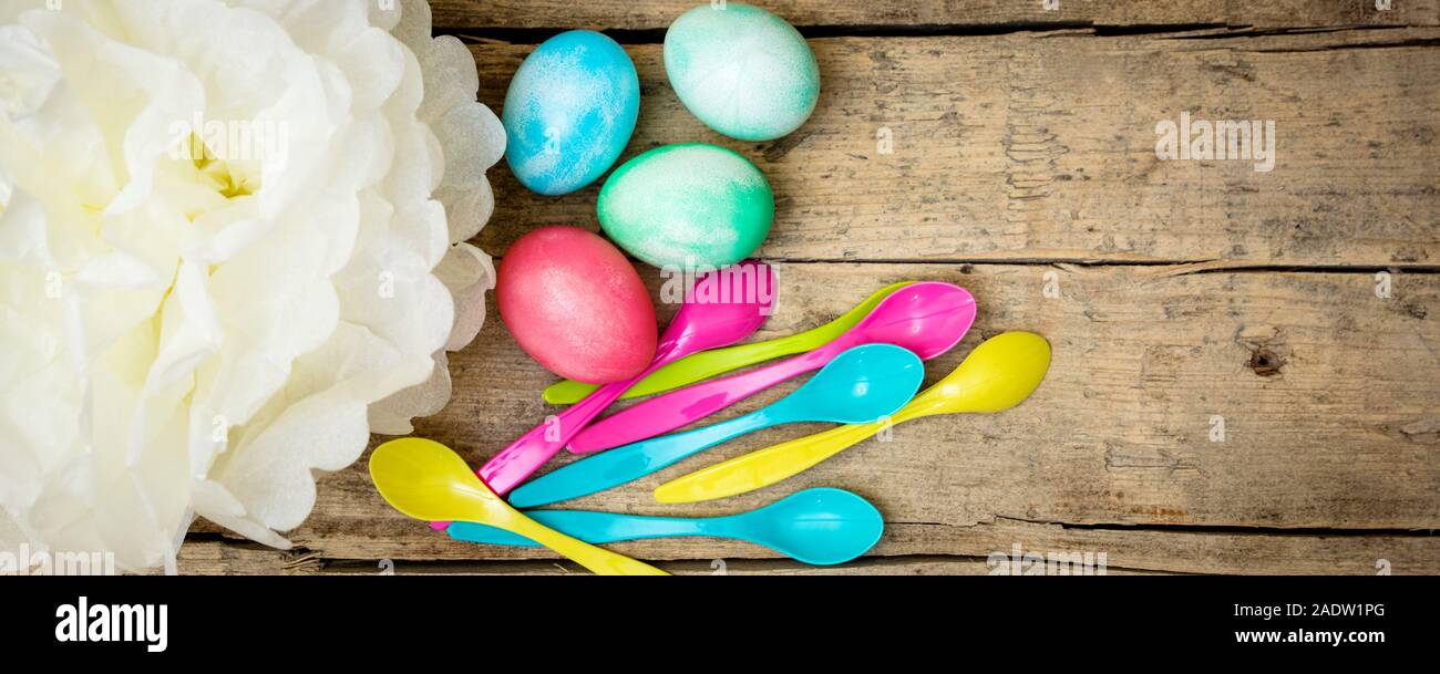 En-tête de Pâques, oeufs de pâques teints colorés et les cuillères avec une fleur en papier sur fond de bois, copyspace Banque D'Images