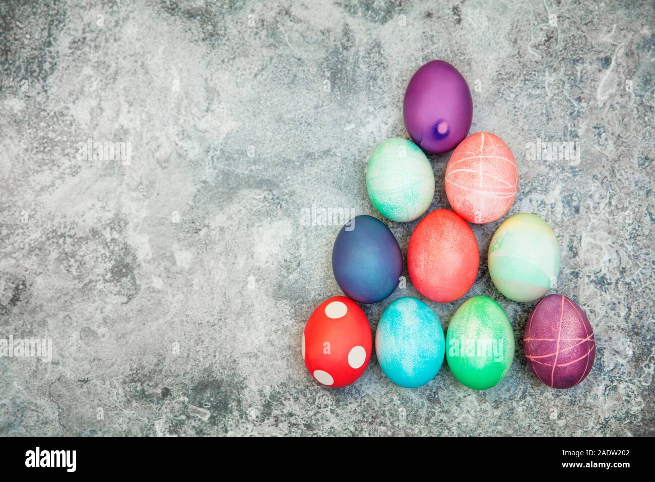 Flatlay avec copyspace, oeufs de pâques teints colorés sur fond texturé gris pyramidale Banque D'Images