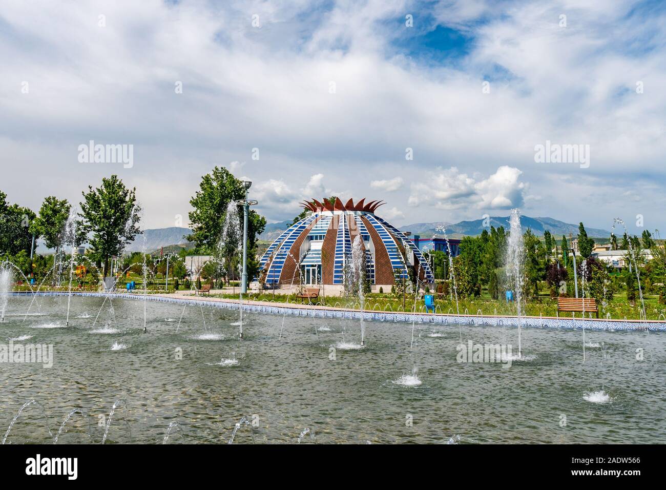Douchanbé Youth Park vue pittoresque de maison en forme de grenade et bassin avec jets d'eau sur un ciel bleu ensoleillé Jour Banque D'Images