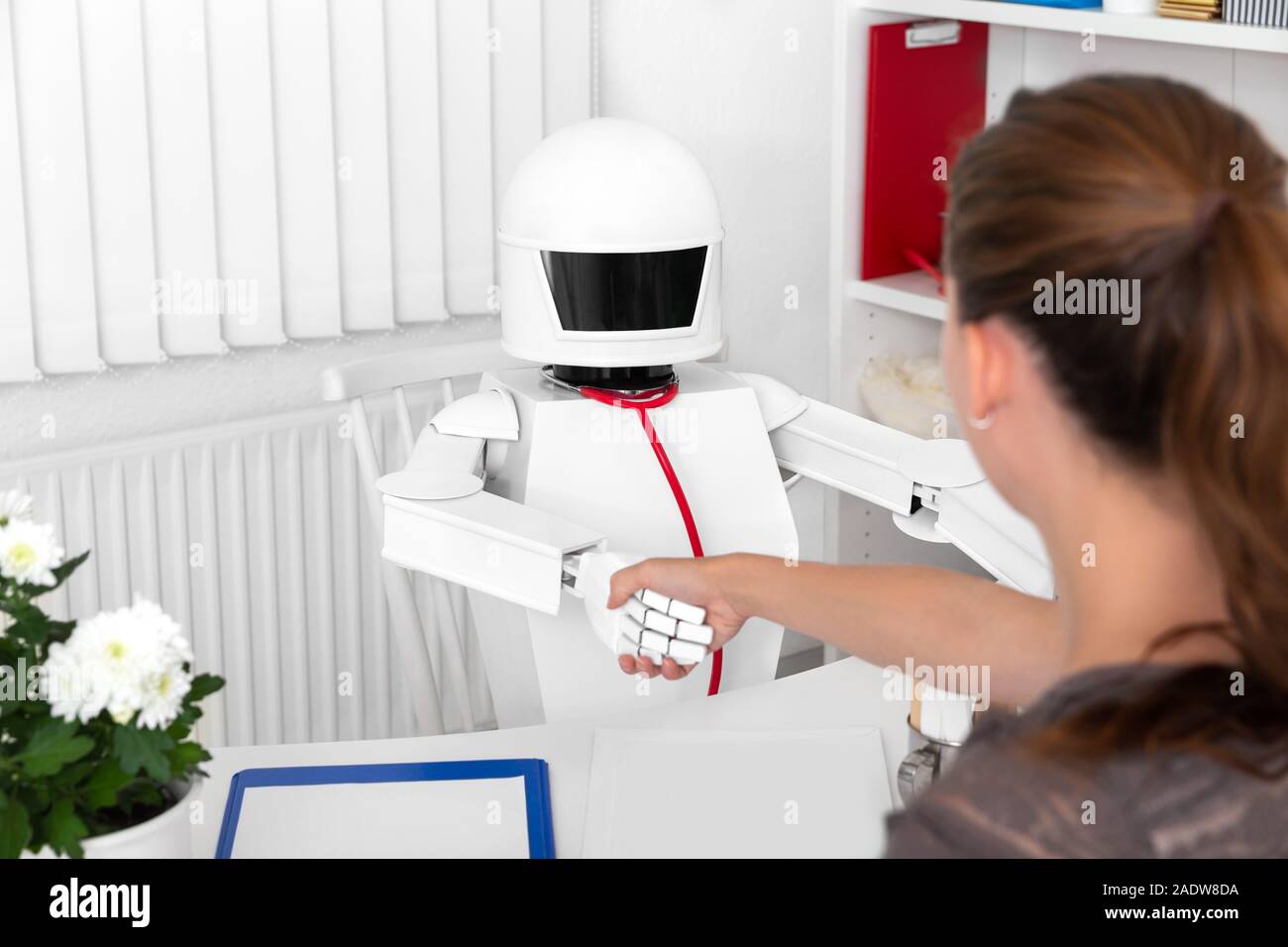 Poignée de main entre une femme et un robot autonome dans son bureau de la médecine ou de la chirurgie Banque D'Images