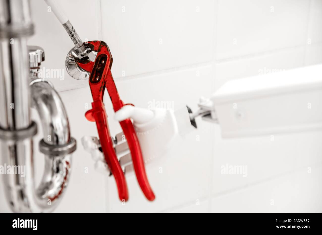 Le robot de service autonome de fixation est quelque chose dans la salle de bain, avec une clé à tube sous le lavabo Banque D'Images