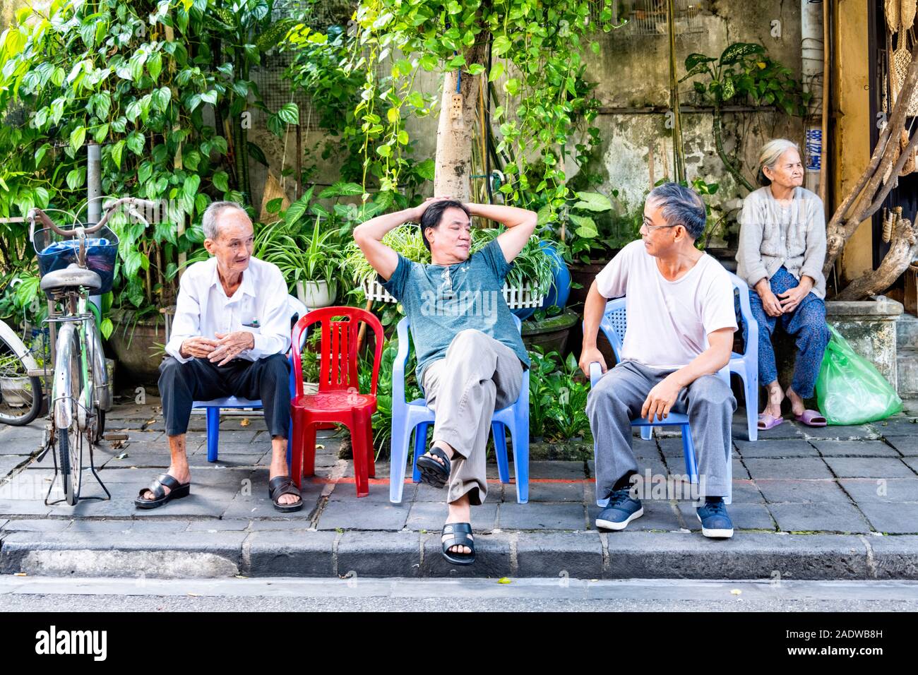 Famille vietnamienne assis sur de petites chaises à l'extérieur de l'atelier à Hoi An, Vietnam Ann Banque D'Images