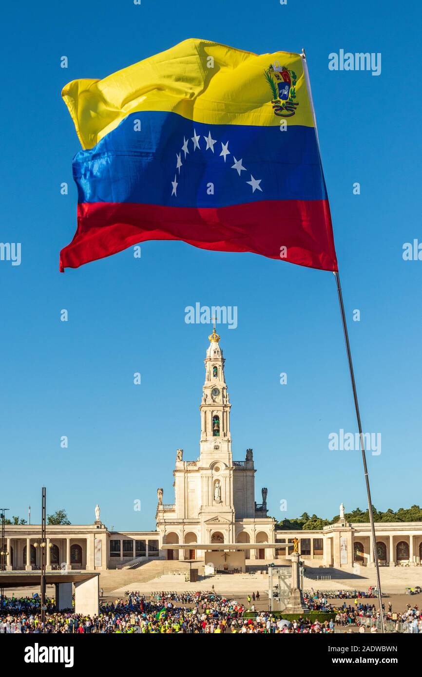 Fatima, Portugal - 12 mai 2019 : Drapeau du Venezuela palpitations dans le sanctuaire de Fatima, au Portugal, avec la basilique en arrière-plan. Banque D'Images