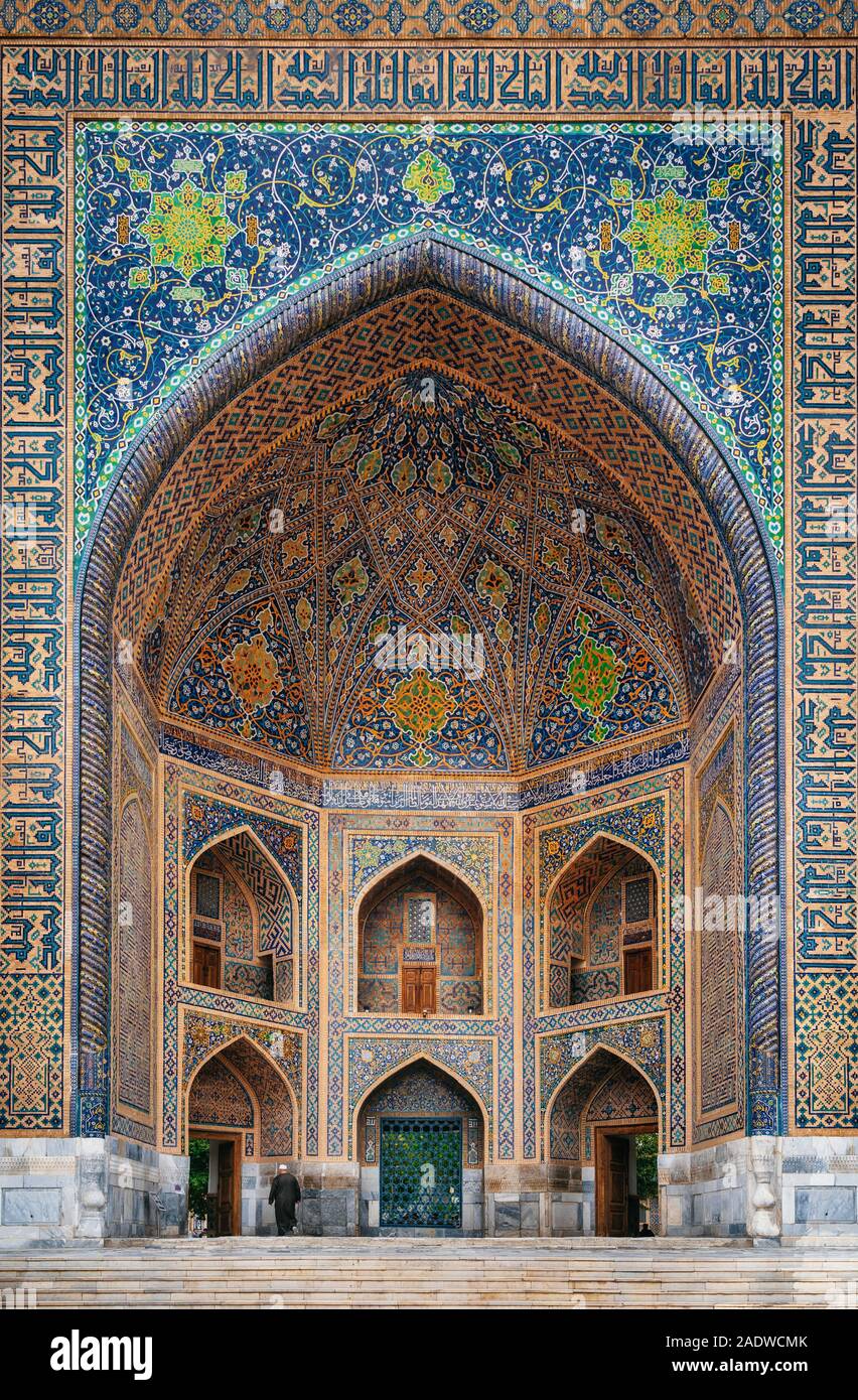 Homme en noir entre dans l'usure Tilya-Kori madrasah dans la ville historique de la place du Registan, Samarqand, Ouzbékistan Banque D'Images