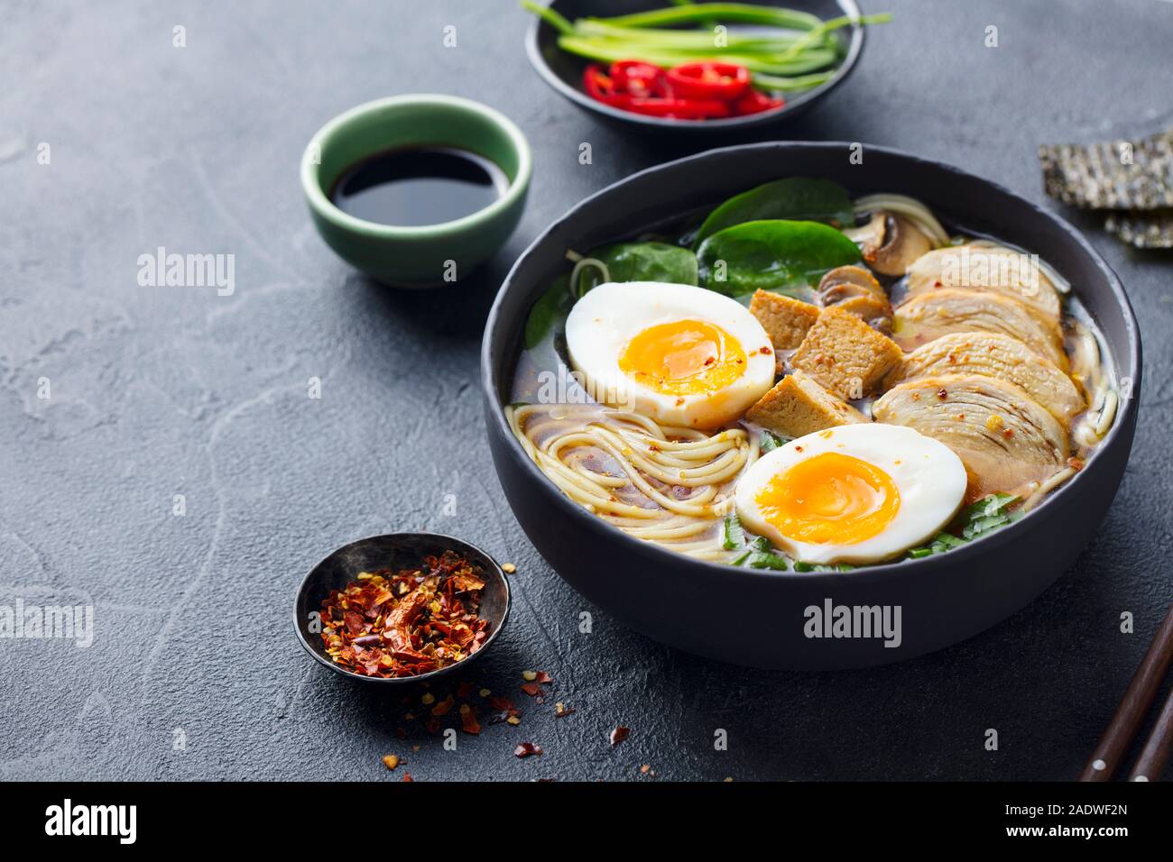 Soupe de nouilles asiatiques, ramen avec du poulet, tofu, légumes et d'oeuf dans un bol noir. Fond d'ardoise. Copier l'espace. Banque D'Images