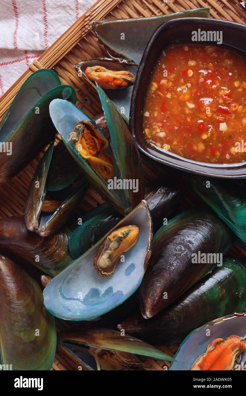 Moules vapeur servant dans le panier de bambou avec une sauce épicée Banque D'Images