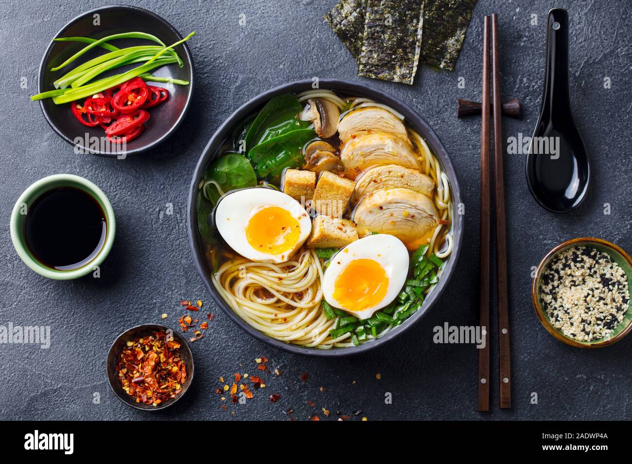 Soupe de nouilles asiatiques, ramen avec du poulet, tofu, légumes et d'oeuf dans un bol noir. Fond d'ardoise. Vue d'en haut Banque D'Images