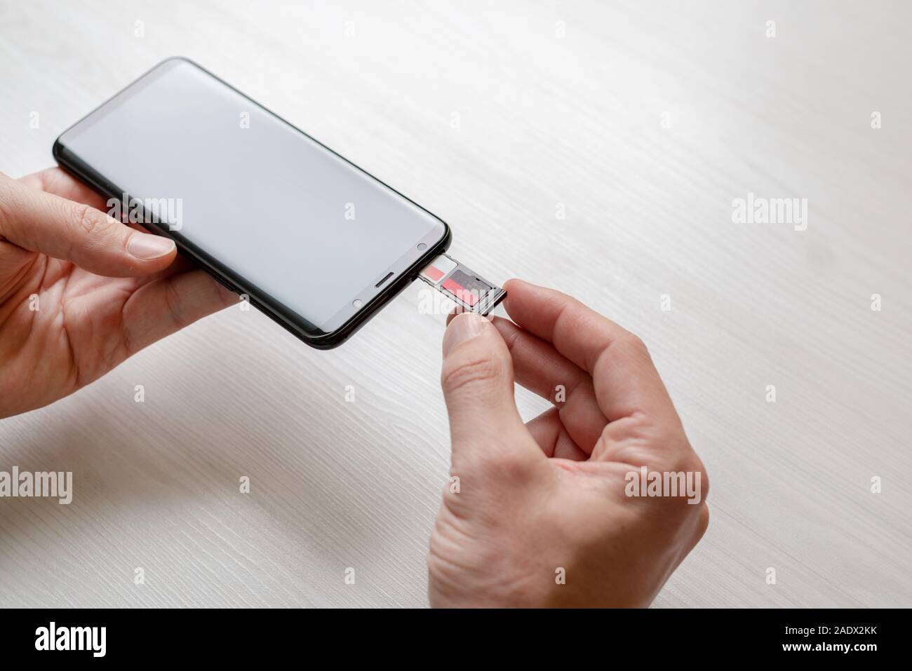 L'insertion de l'adaptateur mini SD et la carte SIM dans le téléphone concept. Main tenant l'adaptateur et l'insère dans le téléphone. Banque D'Images