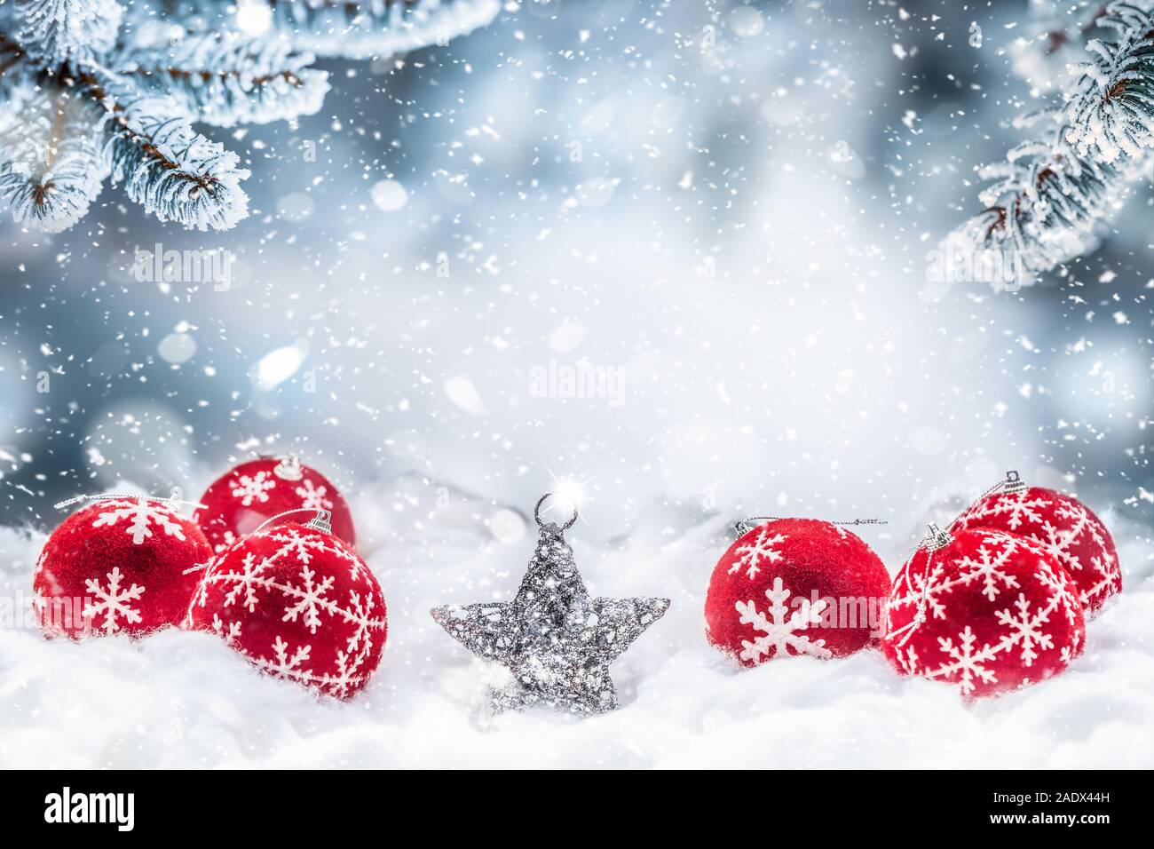 Boules de Noël rouge sur la neige avec des branches de sapin Banque D'Images