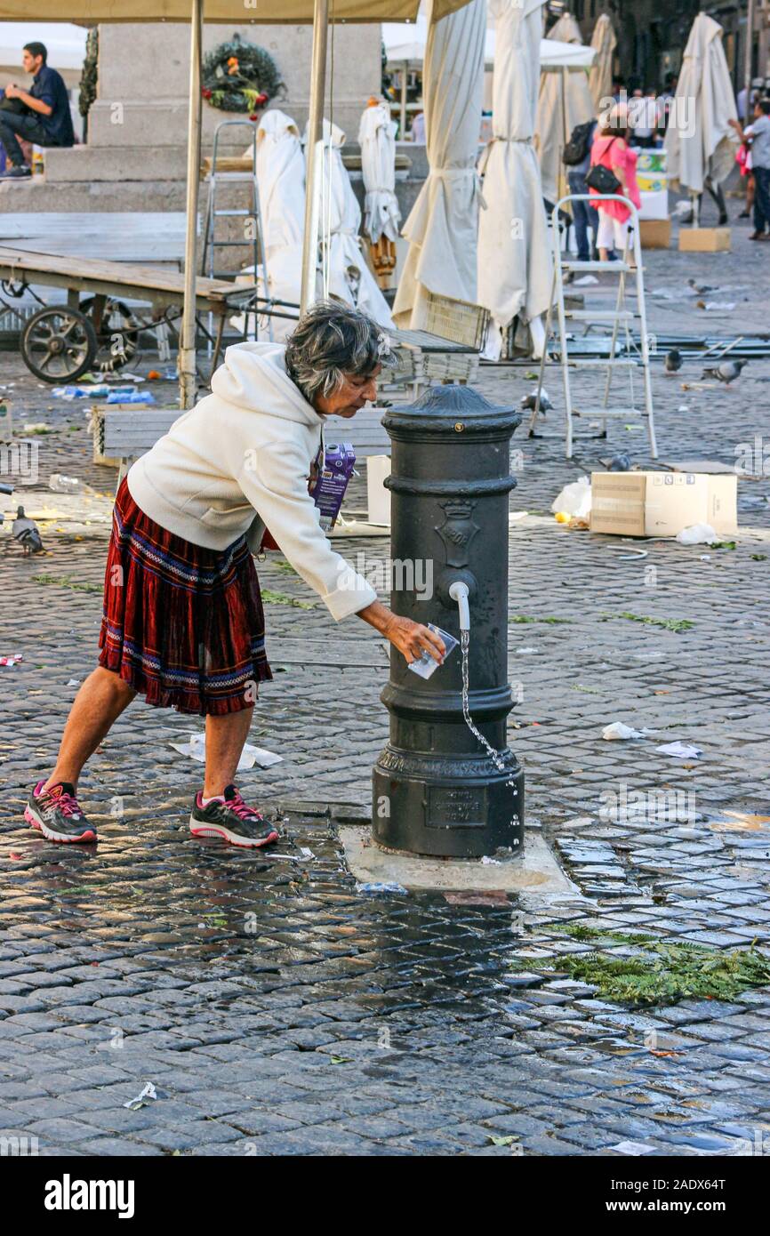 Dame aux cheveux gris obtenir de l'eau potable potable nasone fontaine à Campo de' Fiori, place du marché à Rome, Italie Banque D'Images