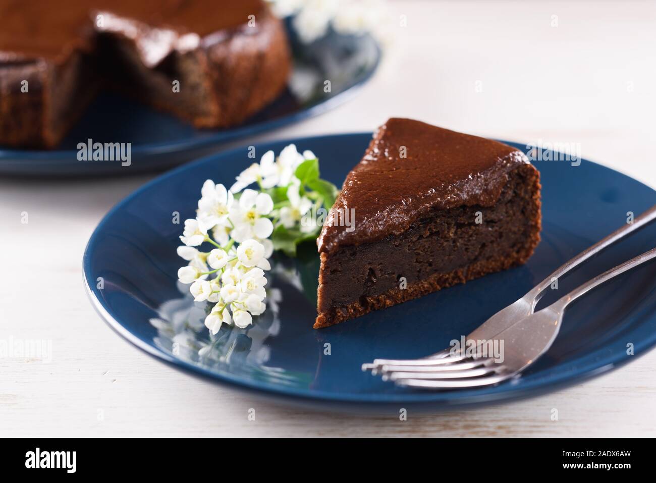 Dessert maison saine. Morceau de gâteau au chocolat et cerises oiseaux oiseau décoré de fleurs de cerisier sur gros plan de la plaque bleu marine Banque D'Images