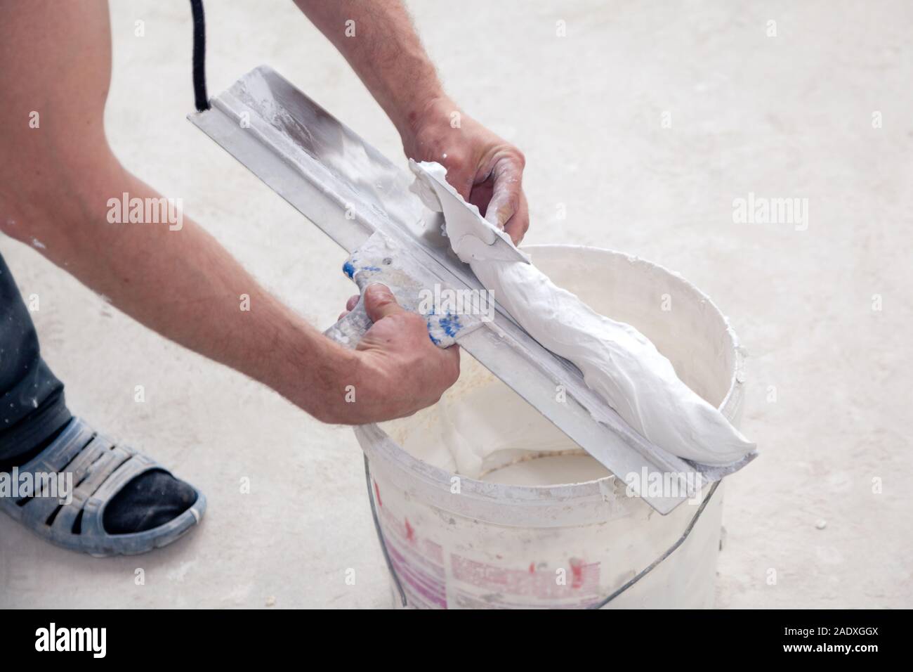 Puttyer spatule holding avec putty solution. Les travaux de construction à l'intérieur concept. Builder de ciment décoratif mis à la truelle pour bucke construction Banque D'Images