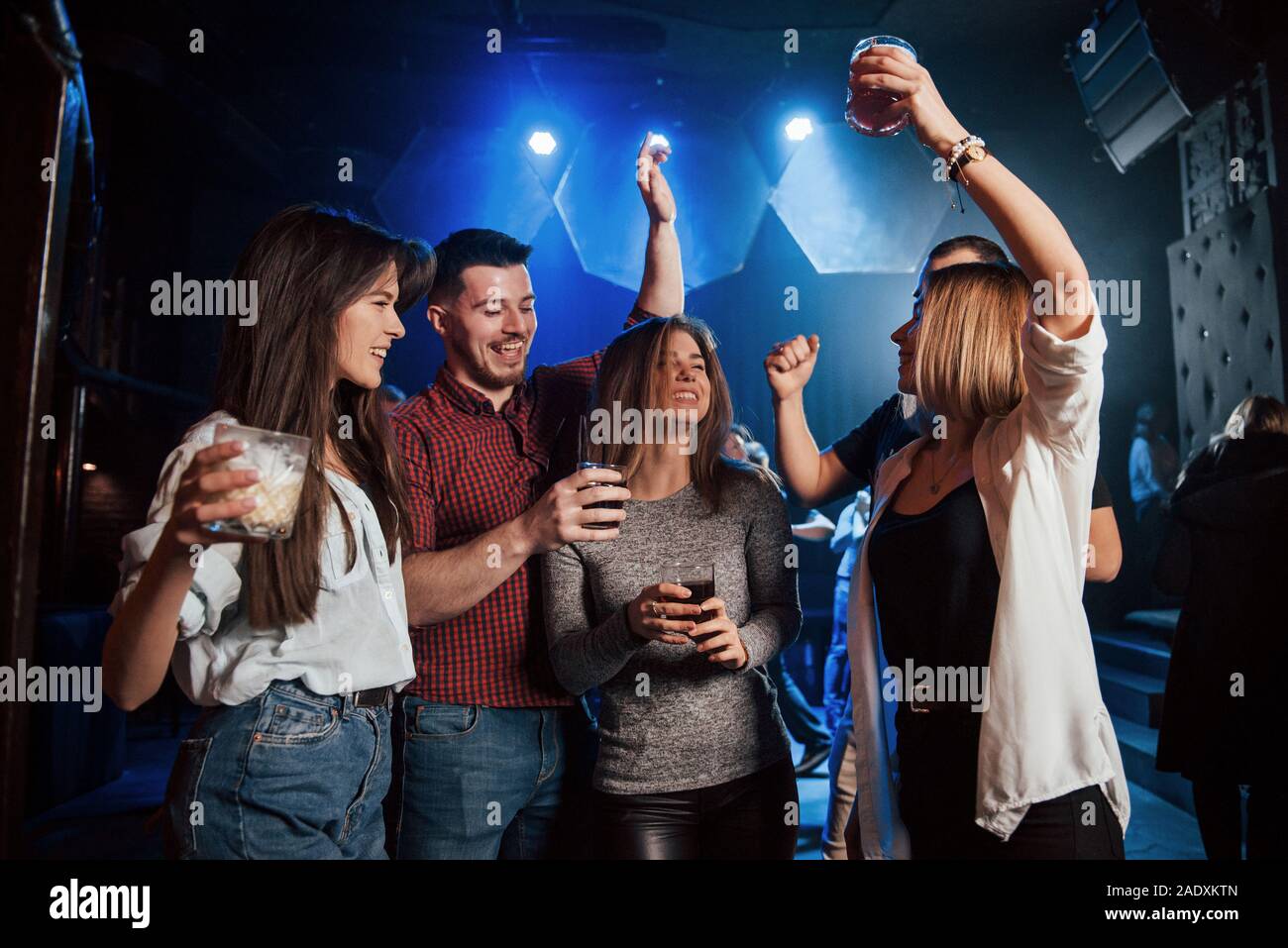 Ne soyez pas timide, montrer tous vos talents. Heureux les gens danser dans la boîte de nuit de luxe avec différentes boissons dans leurs mains Banque D'Images