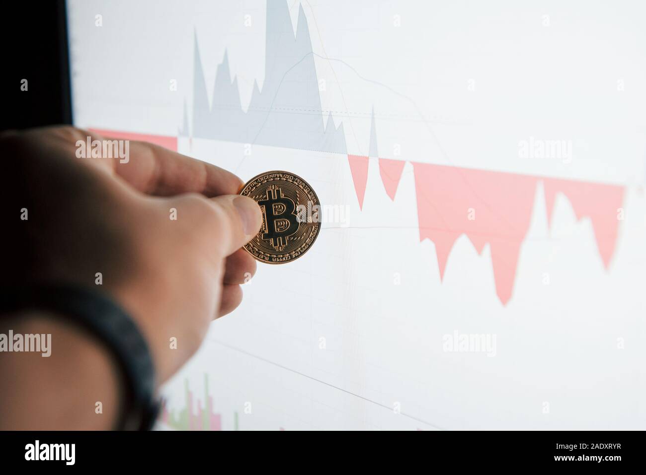 Axé photo. Man's hand holding en bitcoin contre bureau moderne avec moniteur graphique Banque D'Images