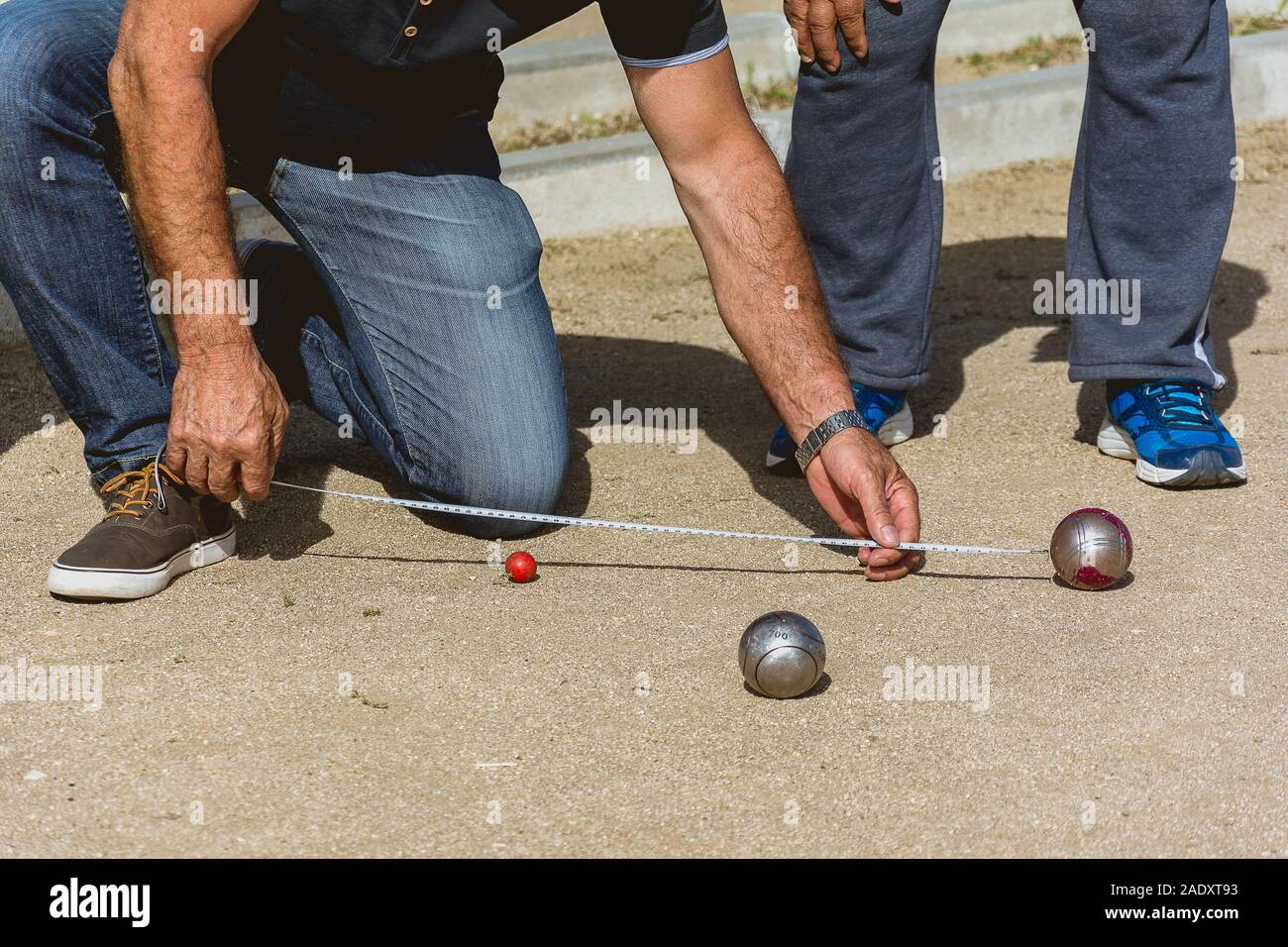 Des cadres supérieurs de mesurer la distance en jeu de boules dans un parc à l'extérieur Banque D'Images
