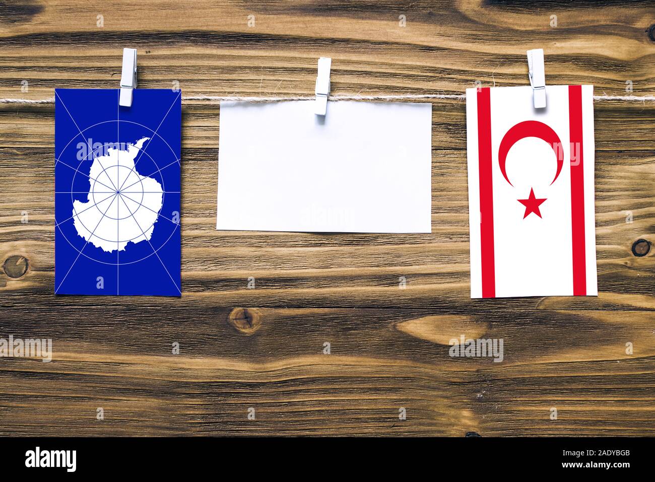 Drapeaux suspendus de l'Antarctique et de Chypre du Nord attaché à la corde avec des pinces à linge avec de l'espace de copie sur papier blanc sur fond de bois diplomatique. Banque D'Images