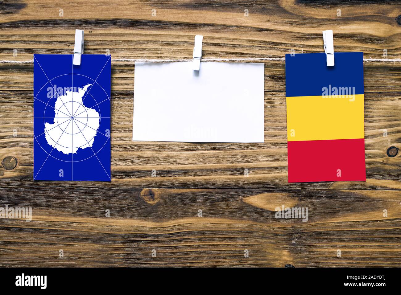 Drapeaux suspendus de l'Antarctique et la Roumanie attache à la corde avec des pinces à linge avec de l'espace de copie sur papier blanc sur fond de bois diplomatique.relatio Banque D'Images