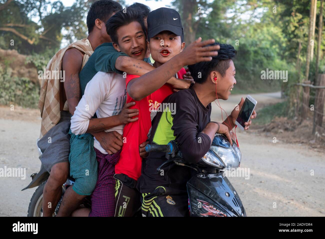Cinq jeunes adolescents birmans rire sur pile à une moto et à travers leur village le long de la rivière Chindwin, dans le nord-ouest de Myanmar (Birmanie) Banque D'Images