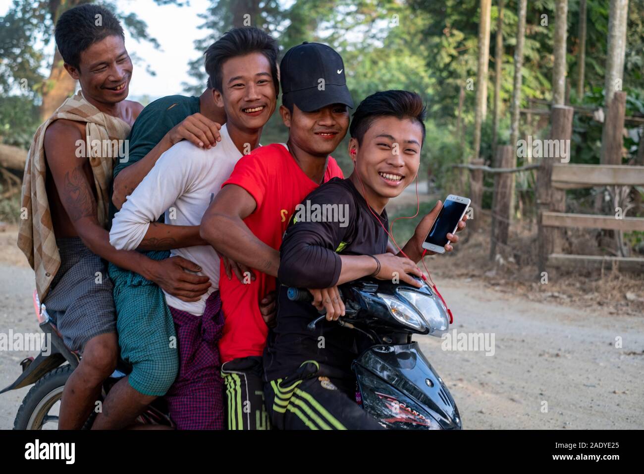 Cinq jeunes adolescents birmans rire sur pile à une moto et à travers leur village le long de la rivière Chindwin, dans le nord-ouest de Myanmar (Birmanie) Banque D'Images