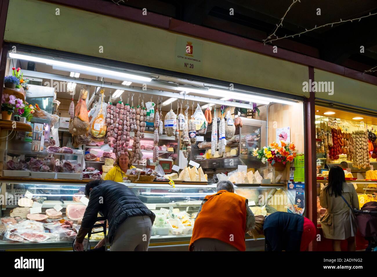 Les Italiens locaux shop pour les viandes à un vendeur à l'intérieur du marché couvert à Vintimille, en Italie. Banque D'Images