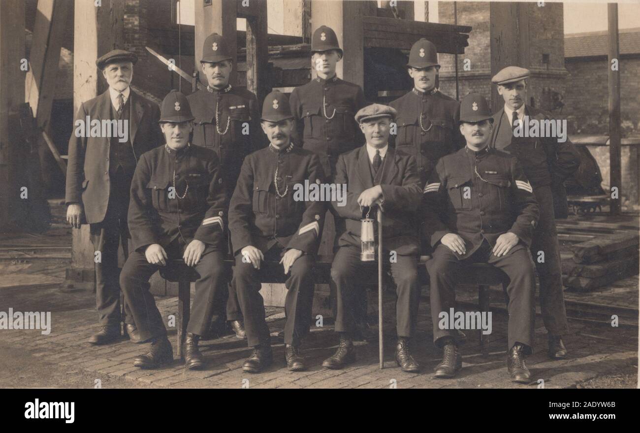 Carte postale photographique vintage du début du XXe siècle montrant un groupe de policiers et de mineurs. Banque D'Images