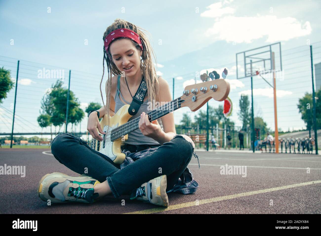 Jolie femme assise avec les jambes croisées et jouant de la guitare Banque D'Images