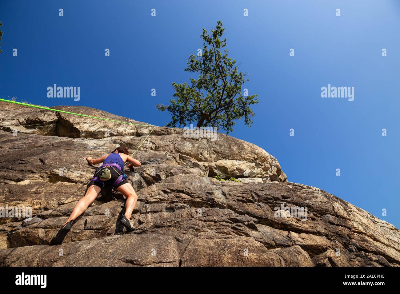 Fille d'aventure est l'escalade d'une falaise abrupte lors d'un coucher du soleil. Pris dans Lighthouse Park, West Vancouver, British Columbia, Canada. Banque D'Images