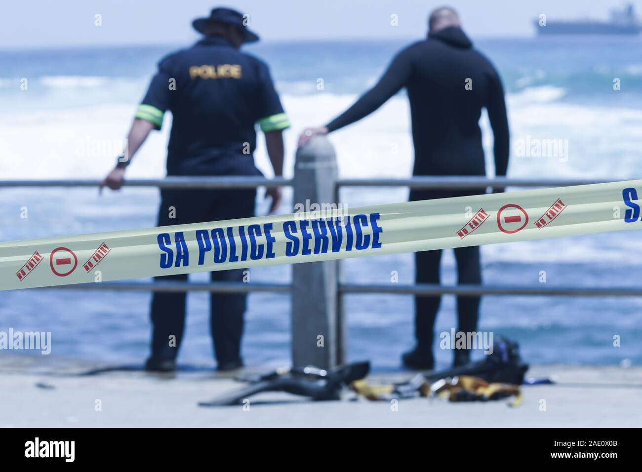 L'unité des services de police sud-africain avec diver derrière la bande adhésive jaune au lieu de crime pendant une opération de recherche et sauvetage sur la côte de Cape Town Banque D'Images