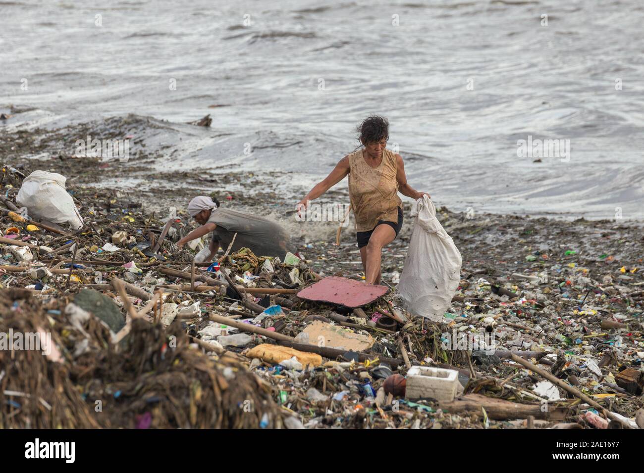 Manille, Philippines - Le 23 août 2017 : une femme la collecte des déchets en plastique dans un tas d'ordures dans la mer Banque D'Images