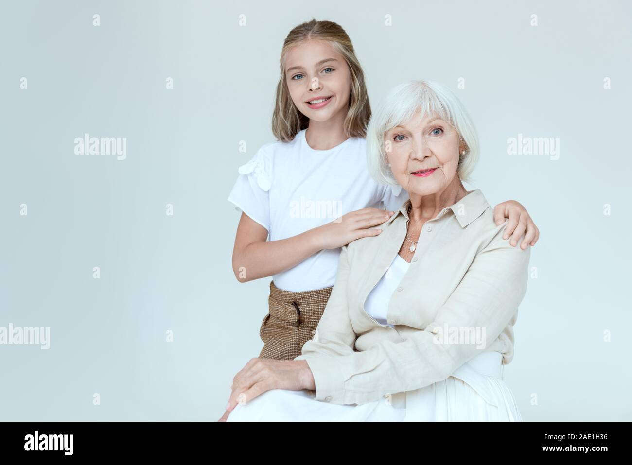 Smiling et mignon granddaughter hugging grand-mère isolé sur gray Banque D'Images