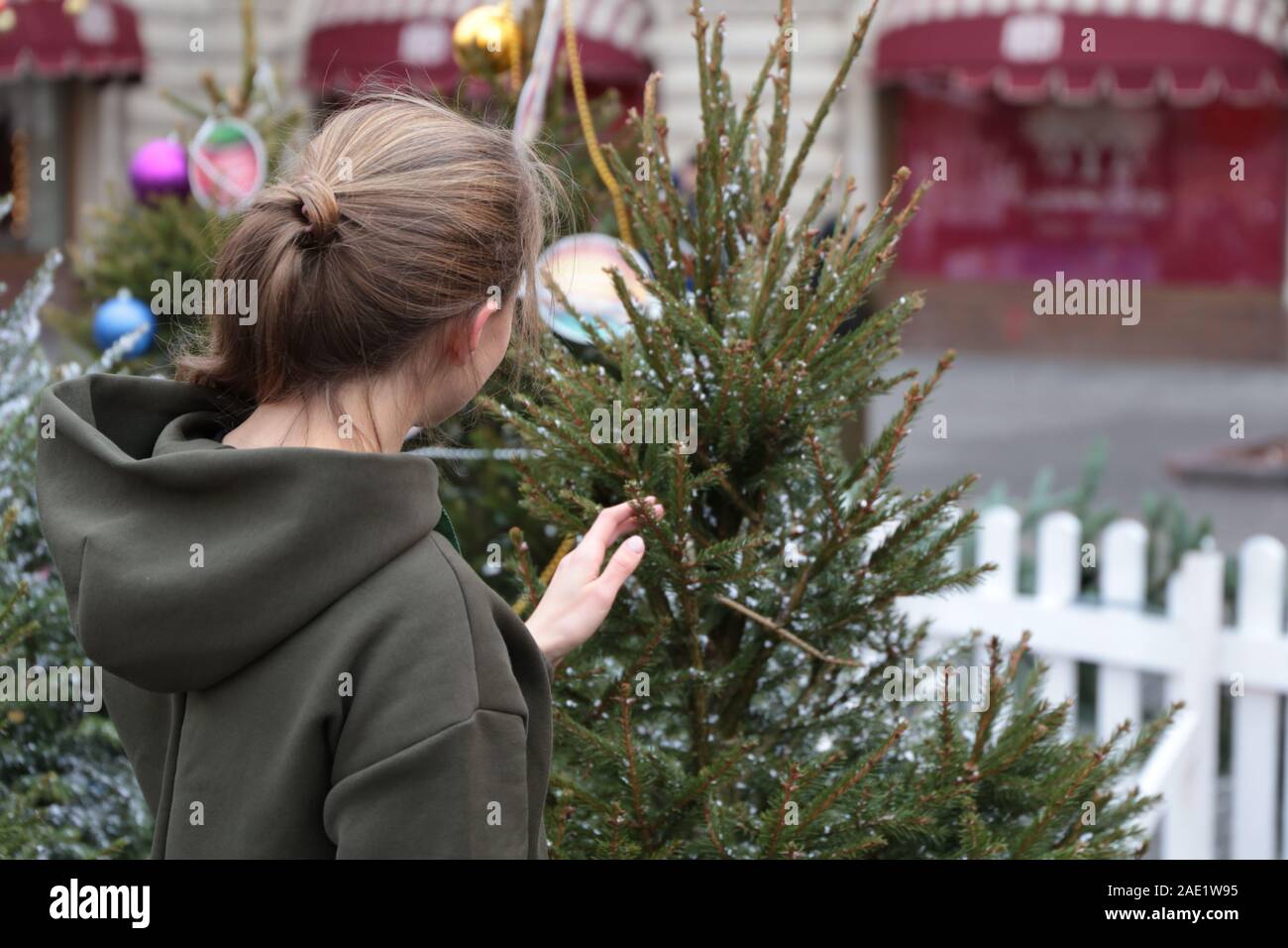 Girl touching arbre de Noël sur une rue couverte de neige. Concept de la fête du Nouvel An, les vacances d'hiver, en ville, de l'acheteur au marché de Noël Banque D'Images