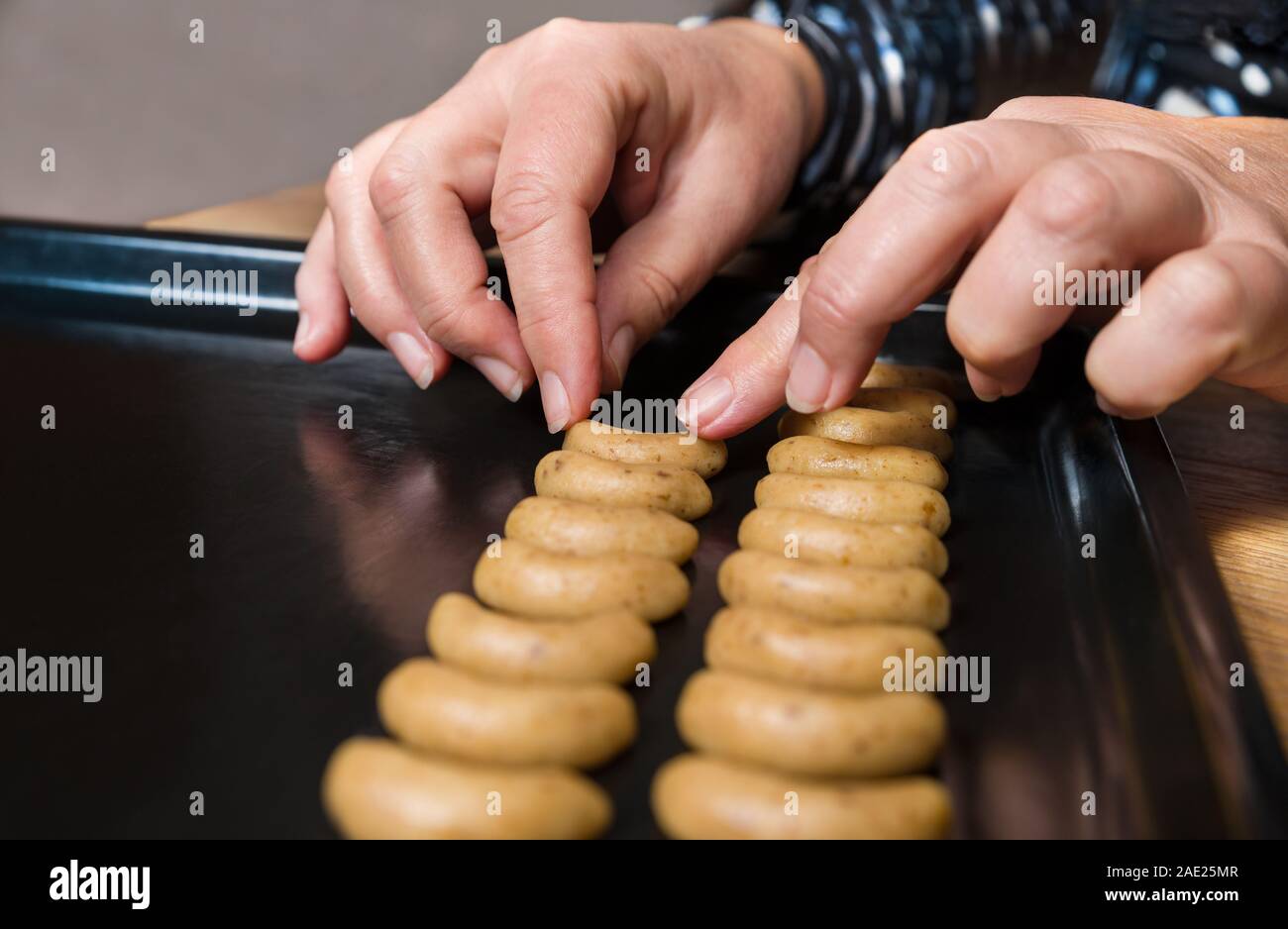 En plaçant les mains des femmes croissant vanille biscuits pâte rouleau noir sur plaque de cuisson pour façonner et Noël traditionnel tchèque noisette mariage bonbons. Pan de feuille. Banque D'Images