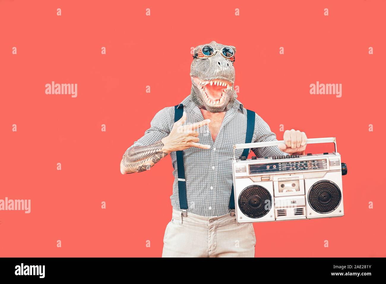 Crazy man wearing mask t-rex tout en écoutant de la musique tenue vintage boombox stereo outdoor - vêtements homme mascarade s'amuser danser Banque D'Images