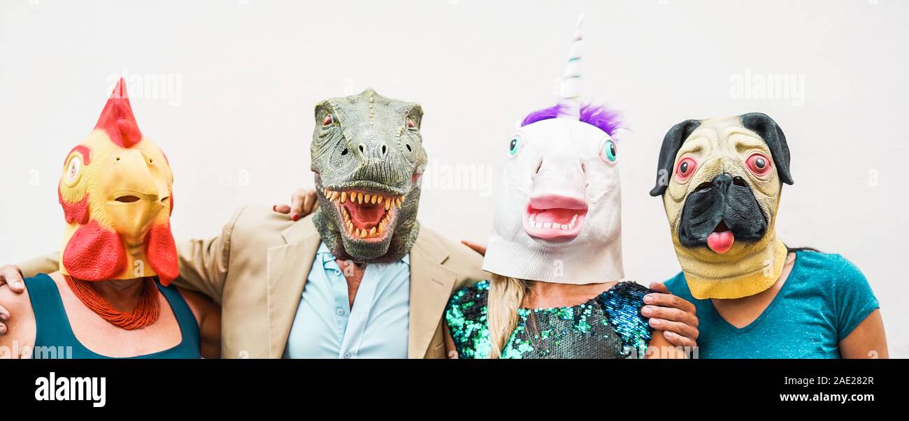 Famille heureuse portant différents masques de carnaval - Crazy people having fun portant sur le poulet, carlino, t-rex et masque de licorne Banque D'Images