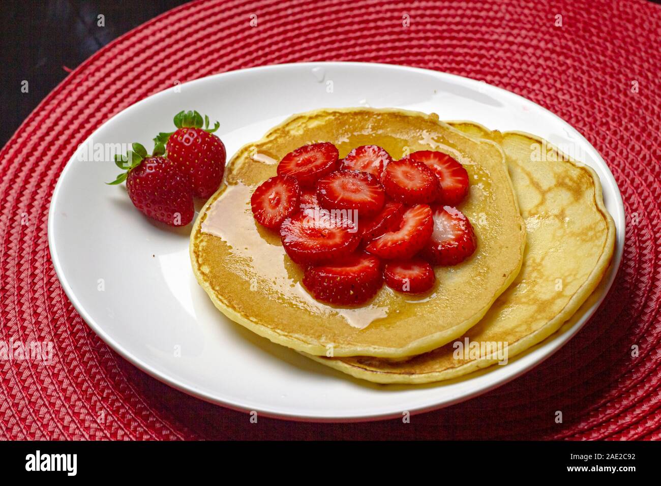 Crêpes faites maison avec des fraises et de sirop dans la plaque blanche Banque D'Images