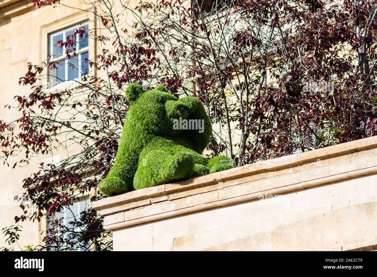 Un modèle d'un ours en gazon artificiel posé à regarder comme si l'ombre de ses yeux tout en regardant depuis le toit d'un bâtiment Banque D'Images