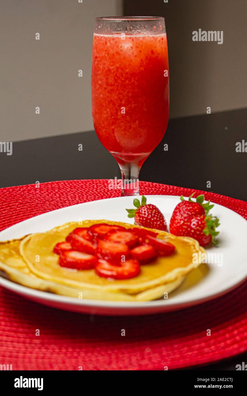 Crêpes faites maison avec des fraises et le sirop dans le plat blanc. Banque D'Images